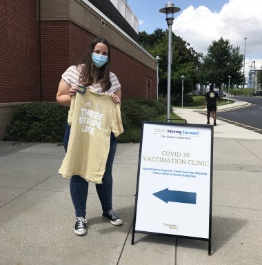 Vaccine clinic volunteer Claire, a third-year student studying biochemistry, holds one of the GT Athletics t-shirts handed out at a recent campus clinic.